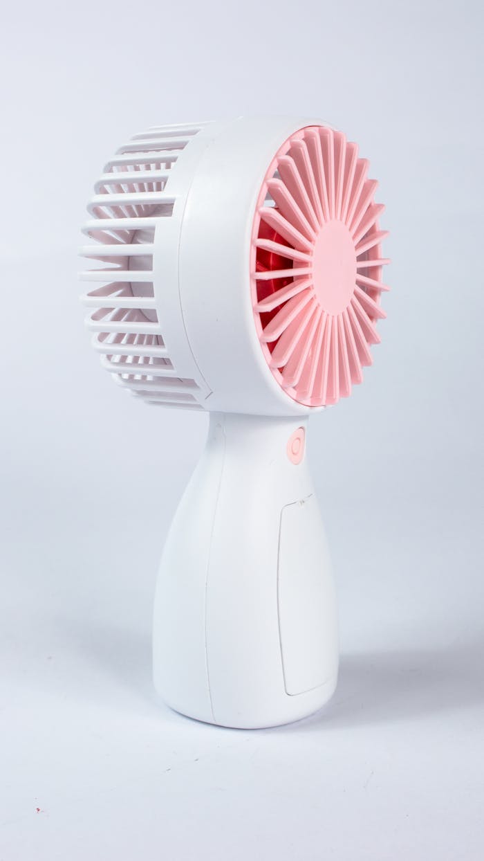 Stylish pink and white portable fan in a minimalist design ideal for cooling needs.